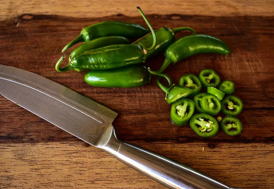 jalapenos on a wooden board with a knife